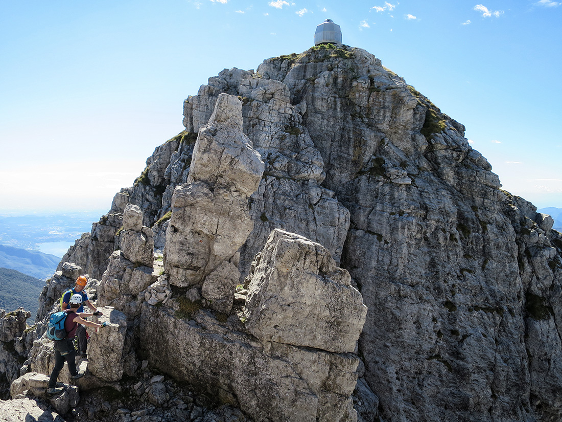 grigne050.jpg - Wir lernten die flotte Monica kennen, die uns anstatt den Standardabstieg Nr.7 zu nehmen woanders runterlotste, östlich um den Berg herum. Das war zum Teil unterhaltsam, zum Teil elends mühsam. Vom Gipfel geht es recht rass an Ketten hinunter. Es kamen einige Personen in voller Klettersteigmontur entgegen. Kann man machen, muss man aber nicht. Die Ketten sind sowieso nicht zum Stürzen ausgelegt, weil die Abstände viel zu lang sind. Hier würde man an den relevanten Stellen 4-6m runter rauschen. Ein KS-Set verhindert hier allenfalls den Komplettabsturz in eine Rinne runter. Aufschlagen würde man vorher schon. Also Hintern zammkneifen und runterhangeln. Wird schon halten!